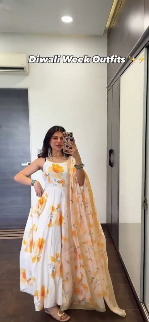 Person wearing a white dress with orange floral patterns in a room.