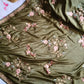 Green fabric with floral embroidery on a light blue background
