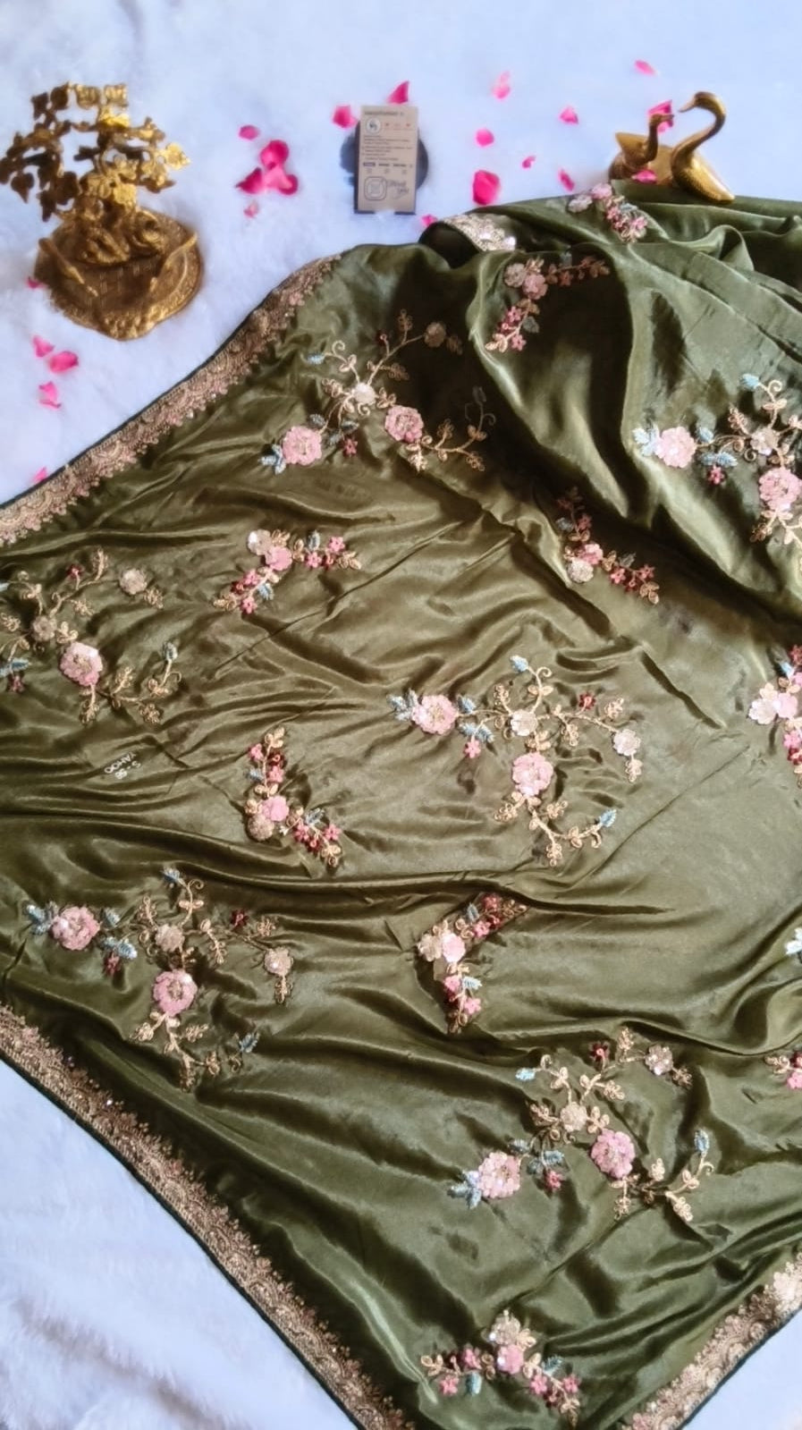 Green fabric with floral embroidery on a light blue background