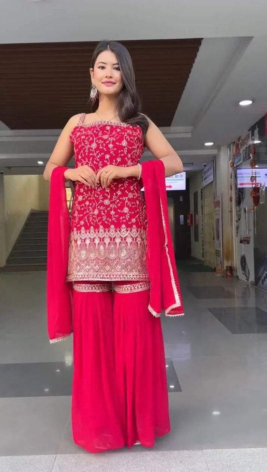 Woman in a red traditional outfit with white patterns in an indoor setting